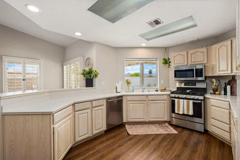 a kitchen with stainless steel appliances granite countertop a stove a sink dishwasher a microwave oven and a refrigerator with wooden floor