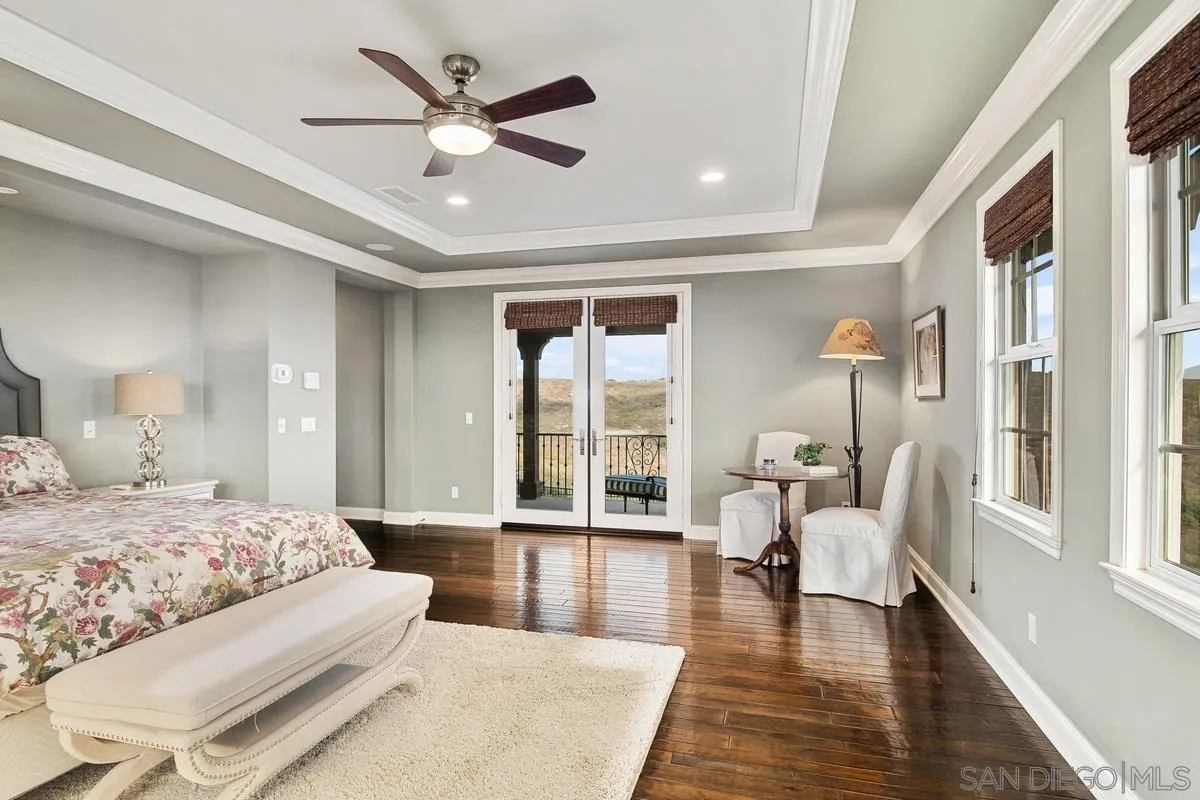 6941 Sitio Cordero Carlsbad, CA 92009 - Photo 16 of 44 a bedroom with a large bed and a large window with wooden floor