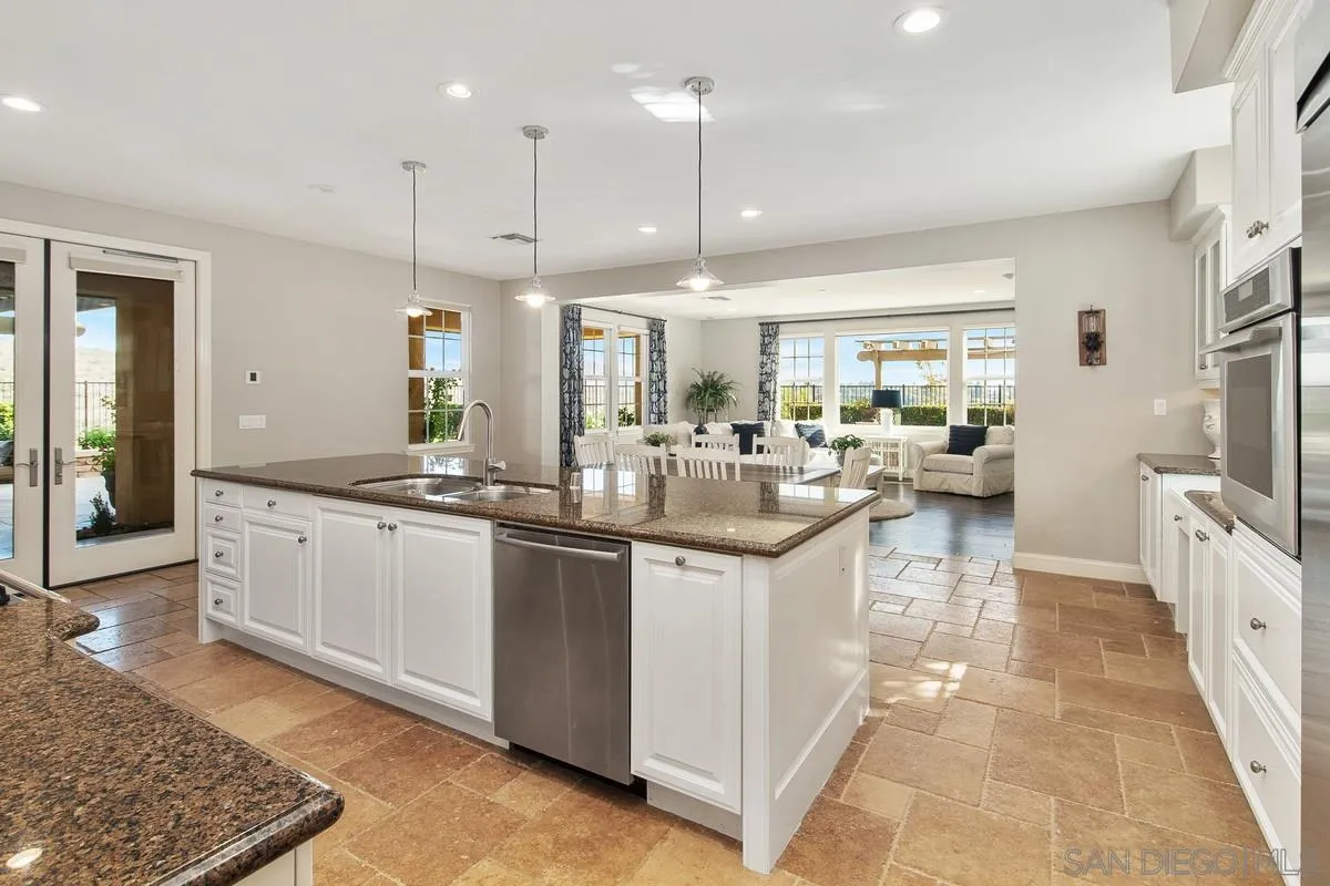 6941 Sitio Cordero Carlsbad, CA 92009 - Photo 7 of 44 a kitchen with stainless steel appliances kitchen island granite countertop a sink and a refrigerator
