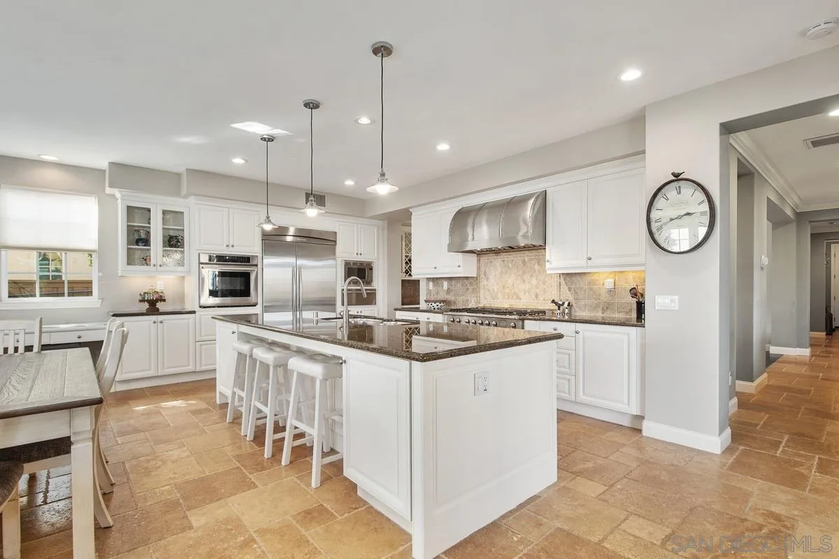 6941 Sitio Cordero Carlsbad, CA 92009 - Photo 9 of 44 a kitchen with stainless steel appliances kitchen island granite countertop a stove a sink a oven with a dining table and chairs