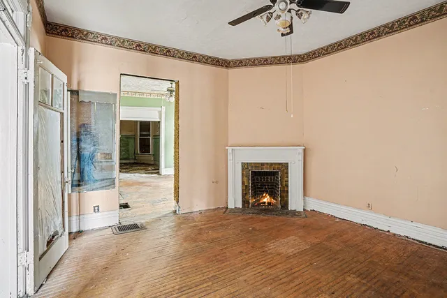 a view of a livingroom with a fireplace a ceiling fan and window