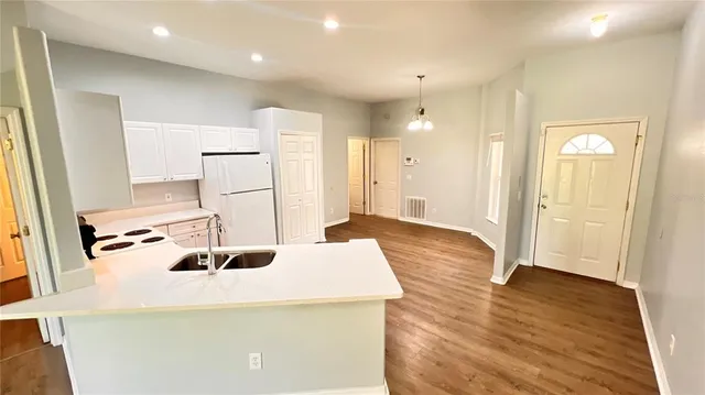 a room with kitchen island a sink wooden floor and glass door
