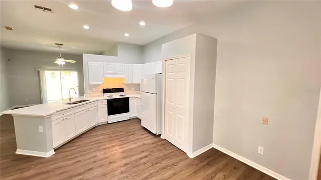 a large kitchen with a refrigerator and white cabinets