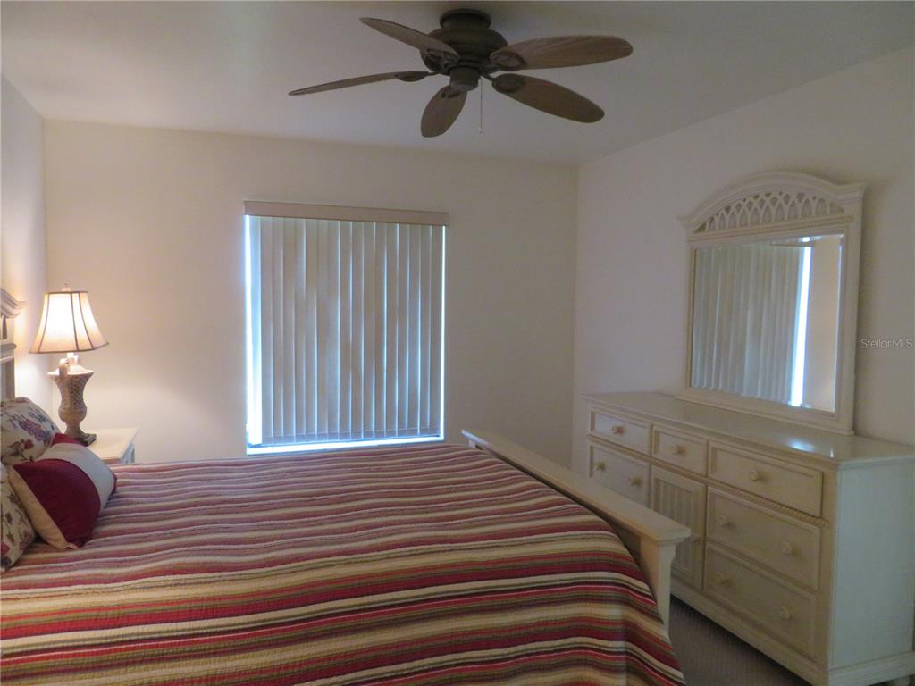 1360 Rio De Janeiro Avenue, Unit 117 Punta Gorda, FL 33983 - Photo 16 of 20 a bedroom with a bed a lamp and a chandelier