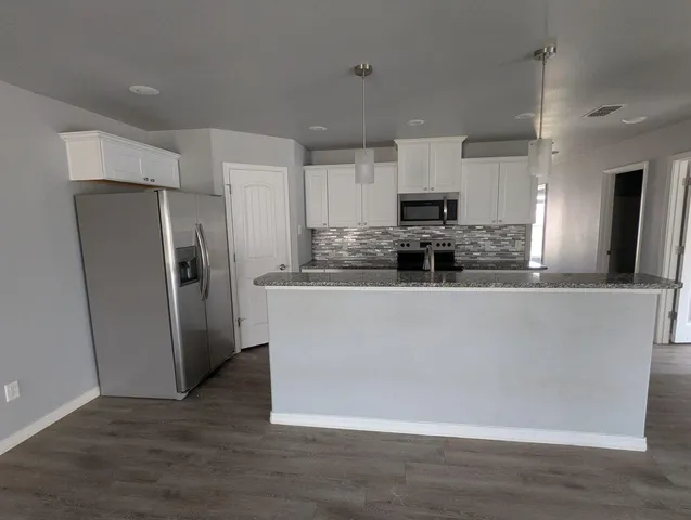 a kitchen with stainless steel appliances granite countertop a refrigerator a stove a sink and a microwave