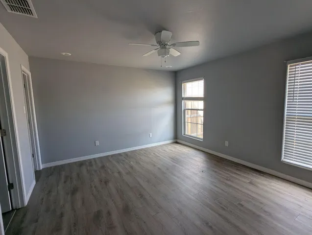 an empty room with wooden floor and windows