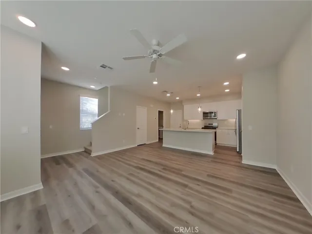 a view of an empty room with window and wooden floor