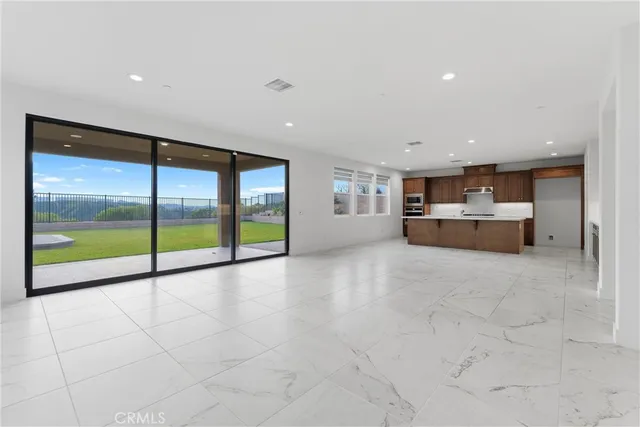 a view of an empty room with a floor to ceiling window and kitchen view