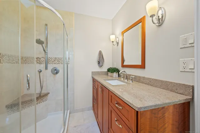 a bathroom with a granite countertop sink a mirror and a shower