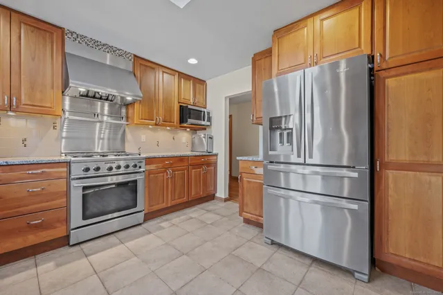 a kitchen with stainless steel appliances granite countertop a refrigerator sink and stove