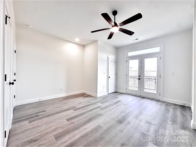 a view of an empty room with wooden floor and a ceiling fan