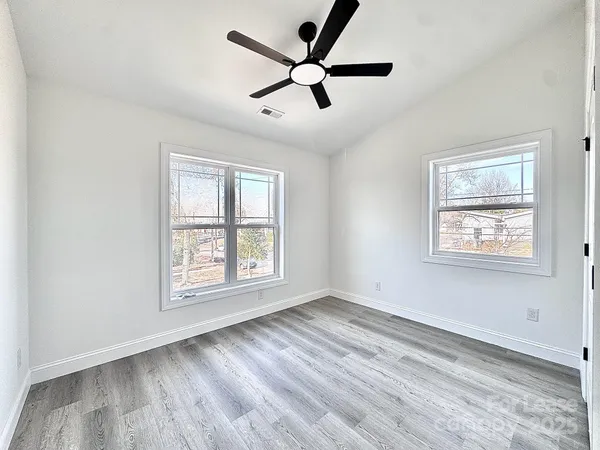 a view of empty room with wooden floor and fan