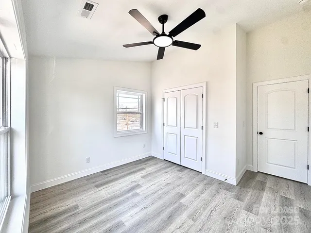a view of empty room with wooden floor and ceiling fan