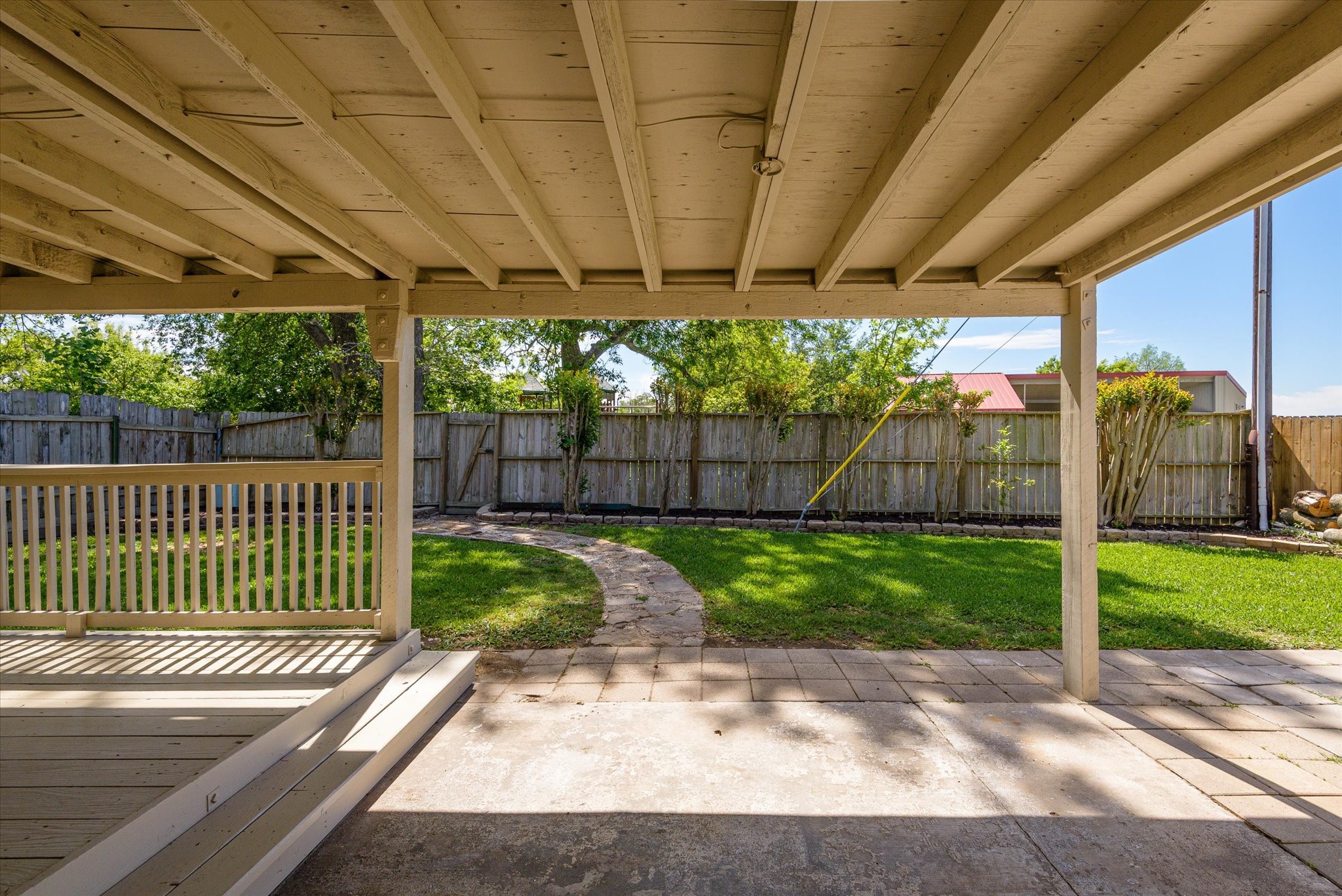 2507 Kings Chapel Road Friendswood, TX 77546 - Photo 19 of 28 From under the covered patio, enjoy a clear view of the backyard with a paved walkway that leads through the lawn. Mature fencing and greenery provide privacy, while the layout offers space for pets, play, or outdoor gatherings.