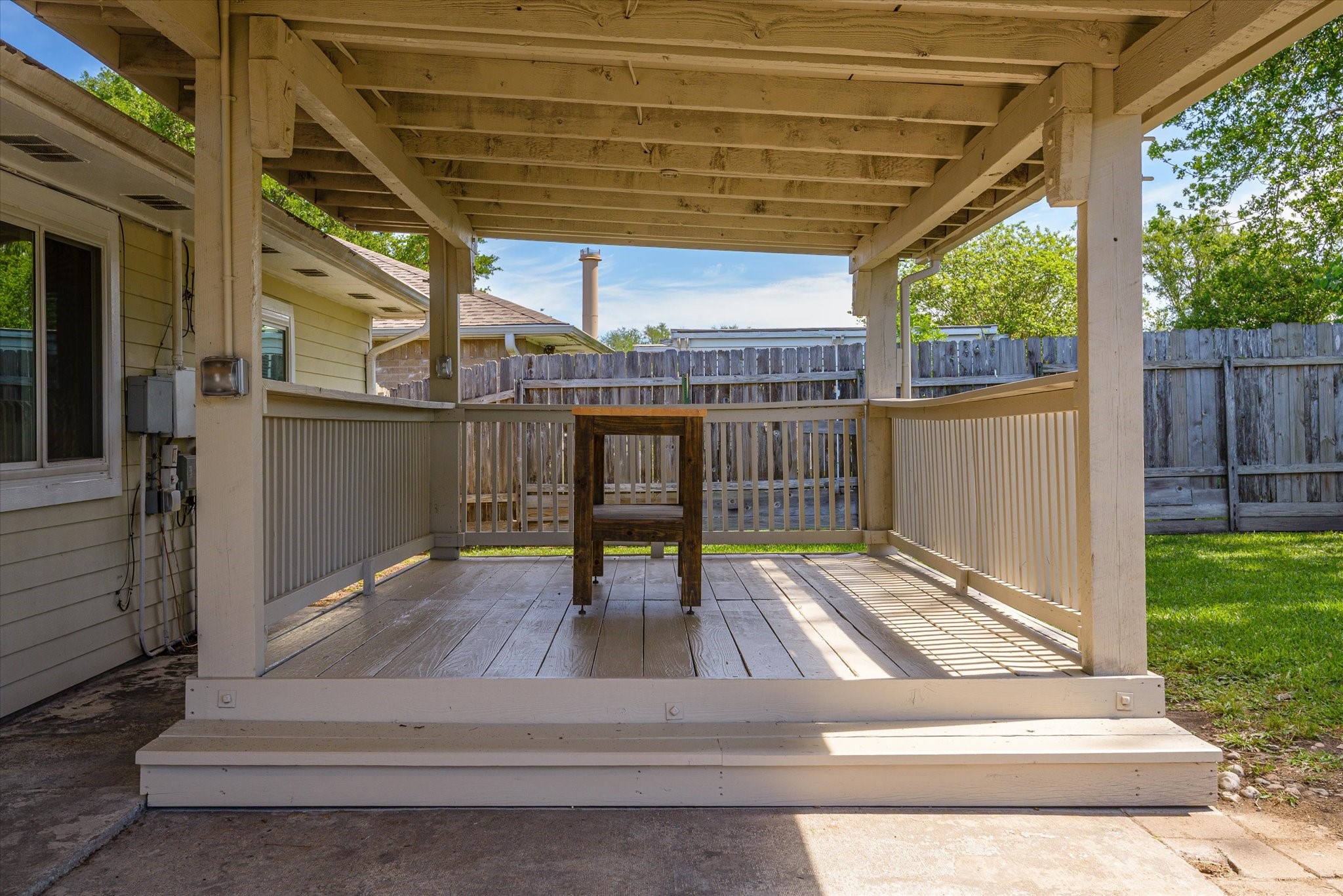 2507 Kings Chapel Road Friendswood, TX 77546 - Photo 20 of 28 Step up onto the elevated deck area of the covered patio, perfect for outdoor seating or grilling. The railing adds definition to the space while still keeping it open to the backyard, creating a comfortable transition between indoor and outdoor living.