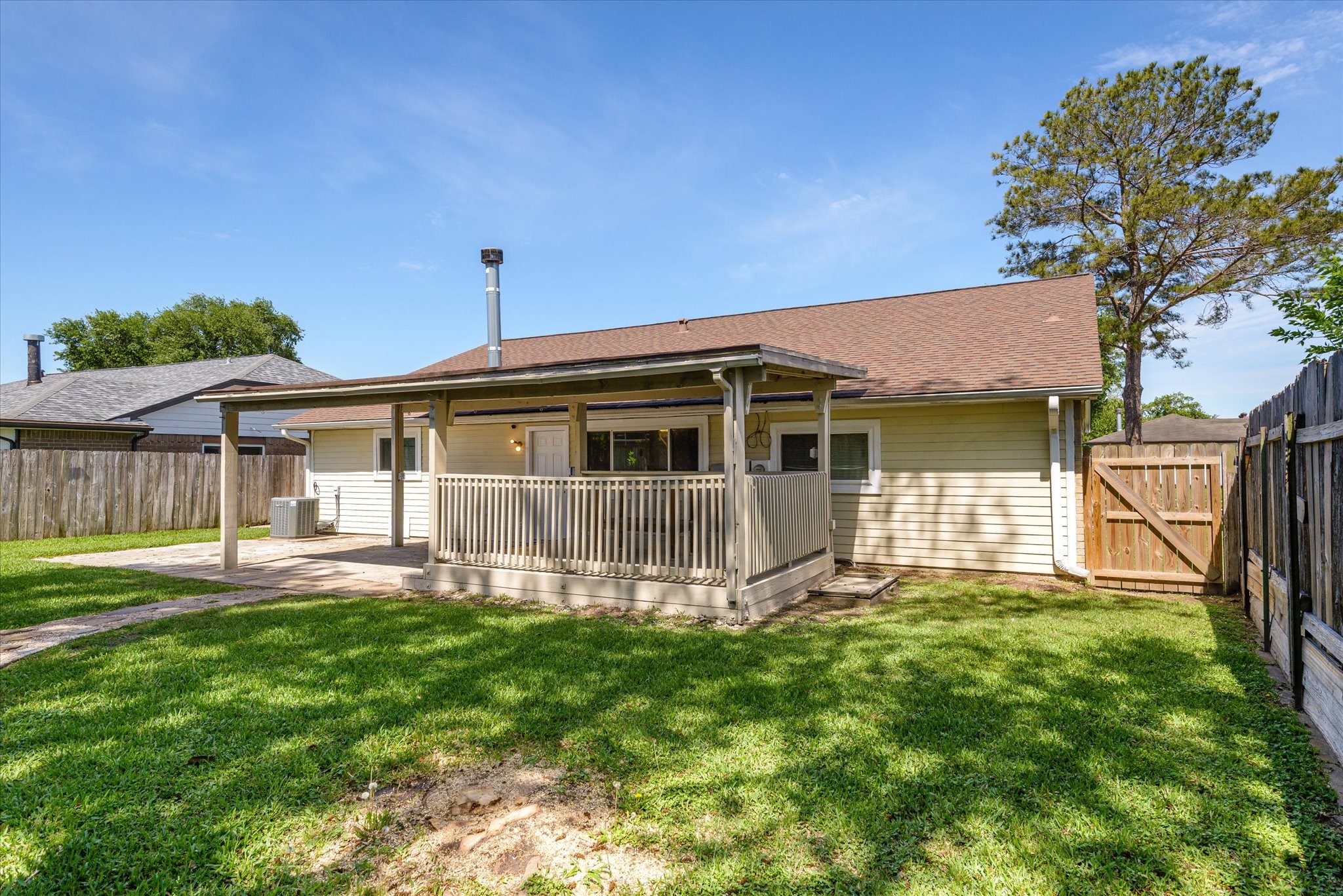 2507 Kings Chapel Road Friendswood, TX 77546 - Photo 21 of 28 A full view of the backyard highlights the covered patio structure, spacious lawn, and gated side access. The layout offers both open green space and defined patio areas, making it easy to enjoy the outdoors in a variety of ways.