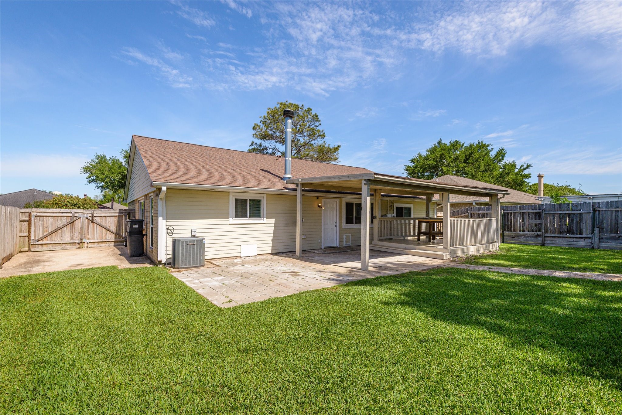 2507 Kings Chapel Road Friendswood, TX 77546 - Photo 22 of 28 From this angle, take in the depth of the yard and the additional paved area off the back of the home. The fencing surrounds the space for privacy, while the setup allows for multiple uses, from entertaining to everyday outdoor living.