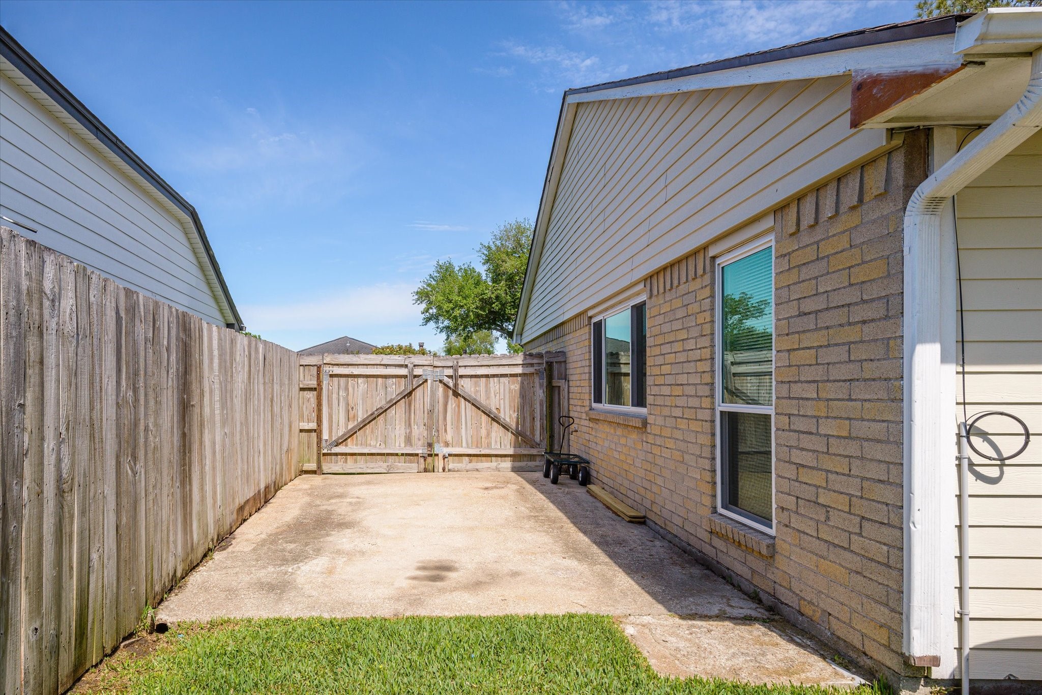2507 Kings Chapel Road Friendswood, TX 77546 - Photo 23 of 28 Along the side of the home, a wide double gate opens to a dedicated concrete parking pad, perfect for storing a boat, trailer, or additional vehicles. This hard-to-find feature adds flexibility and keeps larger items tucked neatly out of sight.