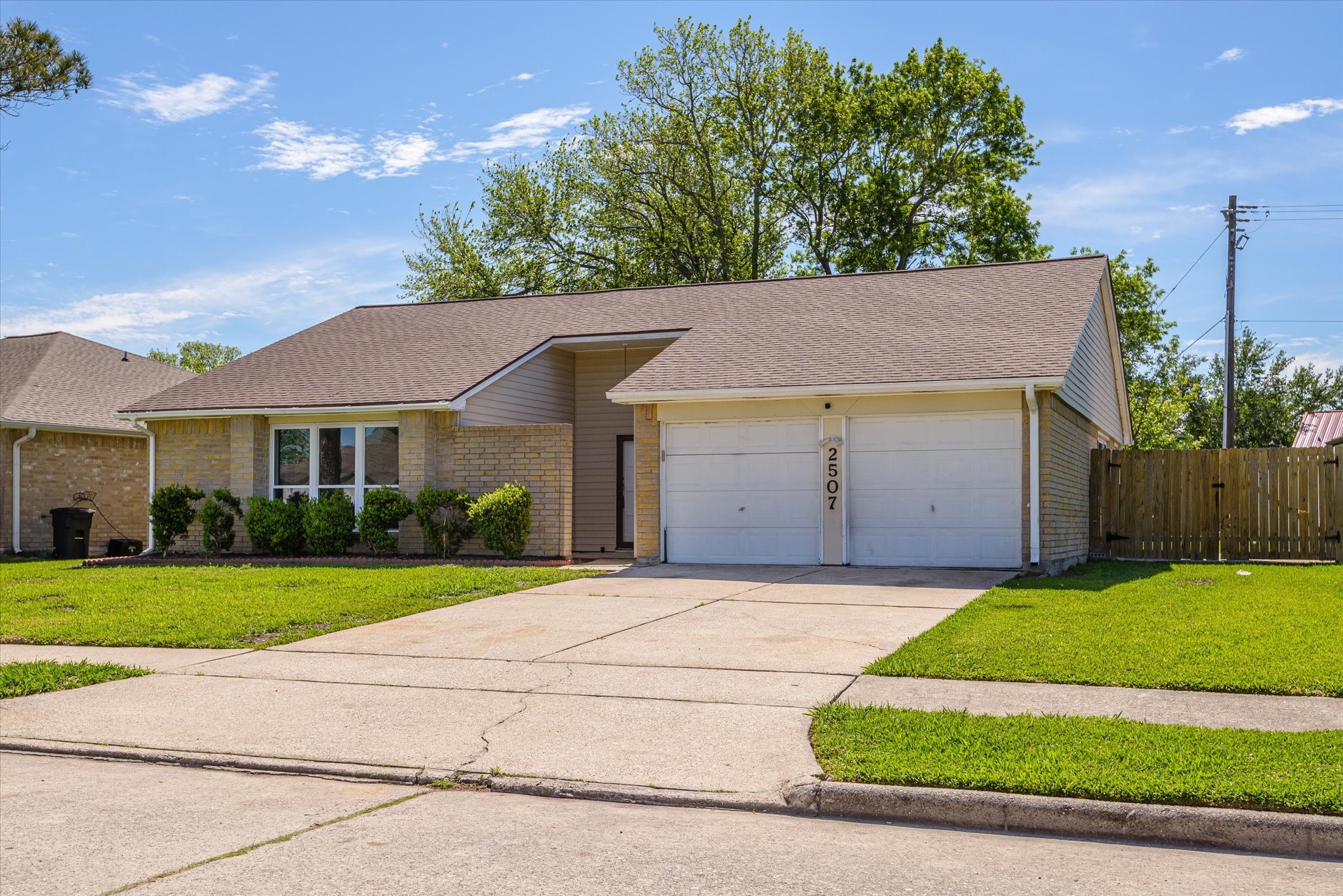 2507 Kings Chapel Road Friendswood, TX 77546 - Photo 3 of 28 From the driveway approach, notice the spacious concrete parking area and side yard access with a wide gate, ideal for storing a boat or RV. The covered entry is tucked for privacy while still offering easy access into the home.