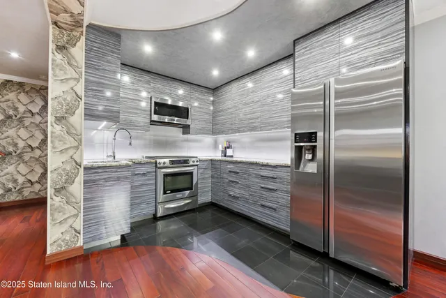 a kitchen with stainless steel appliances kitchen island granite countertop a stove and a refrigerator