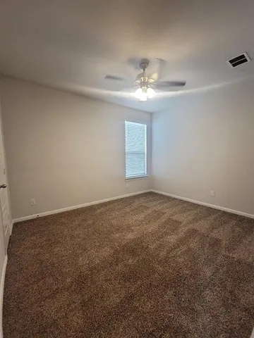 an empty room with a ceiling fan and window