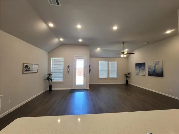 a view of an empty room with wooden floor and a window
