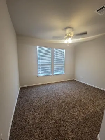 en empty room with windows and ceiling fan
