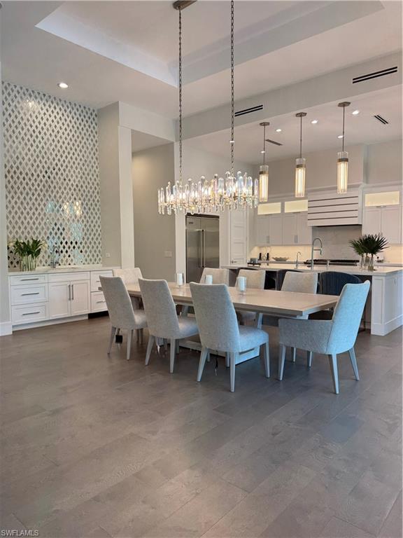 569 Neapolitan Way Naples, FL 34103 - Photo 5 of 50 Dining room featuring dark wood finished floors, a tray ceiling, wallpapered walls, recessed lighting, and an accent wall