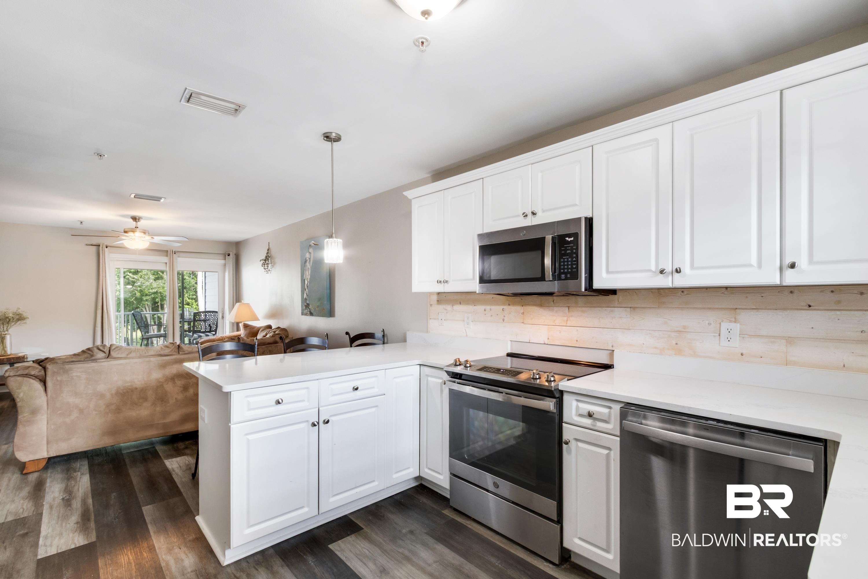 25957 Canal Road, Unit 208 Orange Beach, AL 36561 - Photo 9 of 28 Modern kitchen featuring white cabinetry, stainless steel appliances, quartz countertops, a wood-finish backsplash, and wood-finish flooring