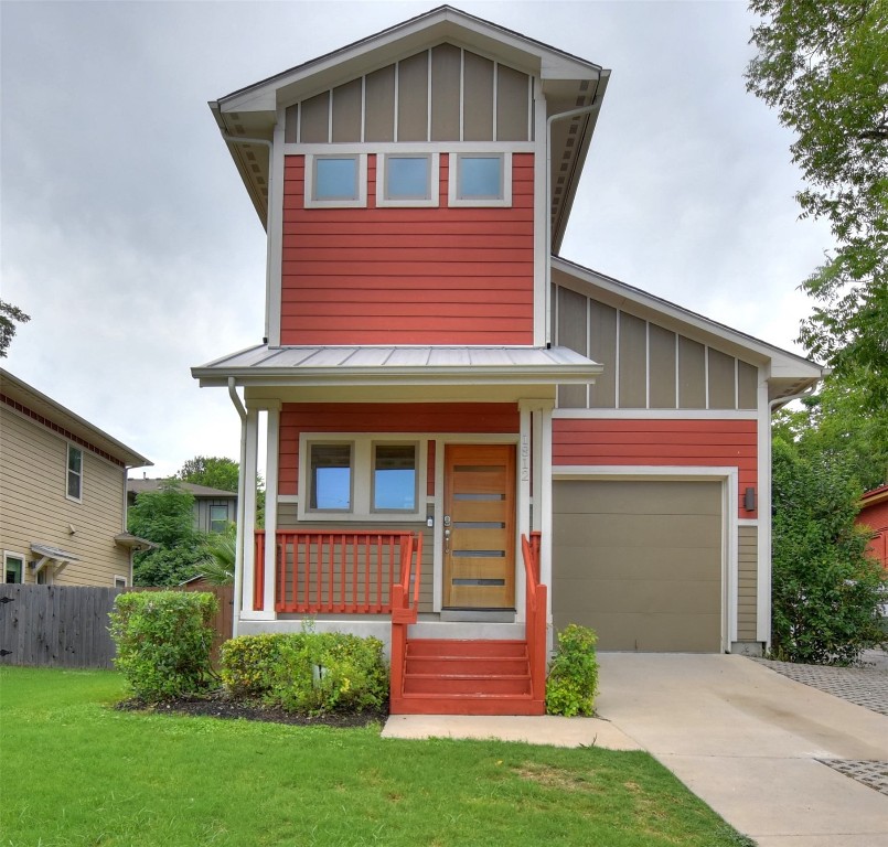 View of front facade with board and batten siding, covered porch, a garage, driveway, and a standing seam roof
