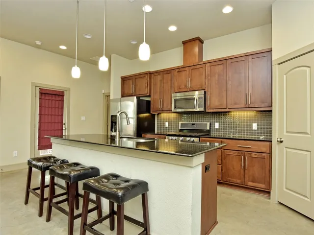a kitchen with stainless steel appliances a stove a sink a microwave a refrigerator and cabinets