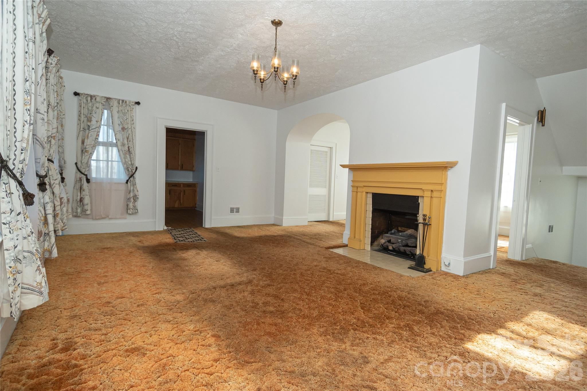 615 Carbon City Road Morganton, NC 28655 - Photo 17 of 42 a view of a livingroom with a fireplace a chandelier and windows