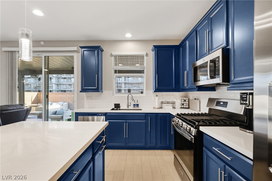 1921 Miller Ridge Avenue North Las Vegas, NV 89031 - Photo 6 of 26 This kitchen showcases blue cabinetry, white countertops, and contemporary appliances.