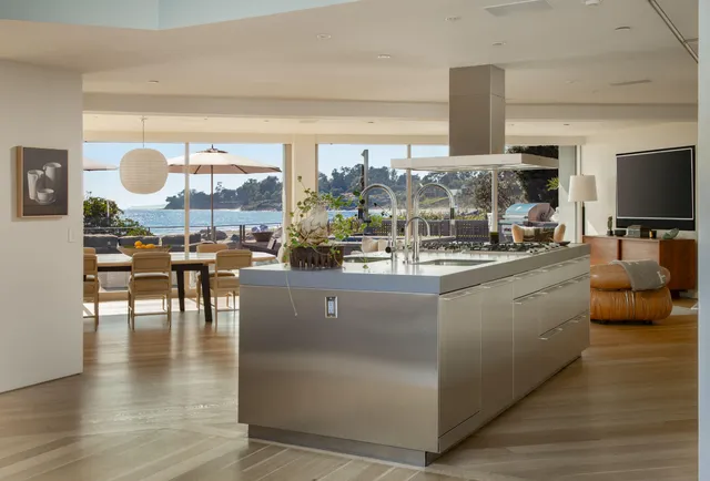 a living room with couches and a flat screen tv with kitchen view