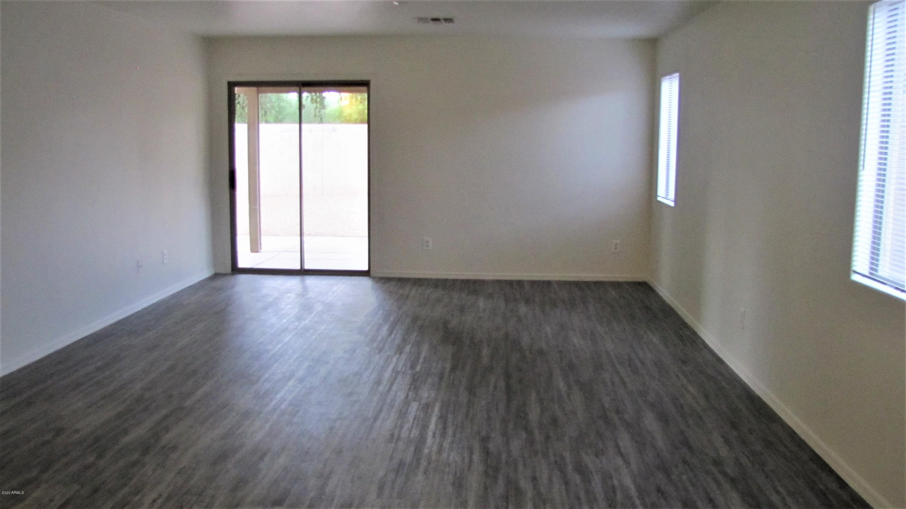 16086 West Calavar Road Surprise, AZ 85379 - Photo 3 of 28 an empty room with wooden floor and windows