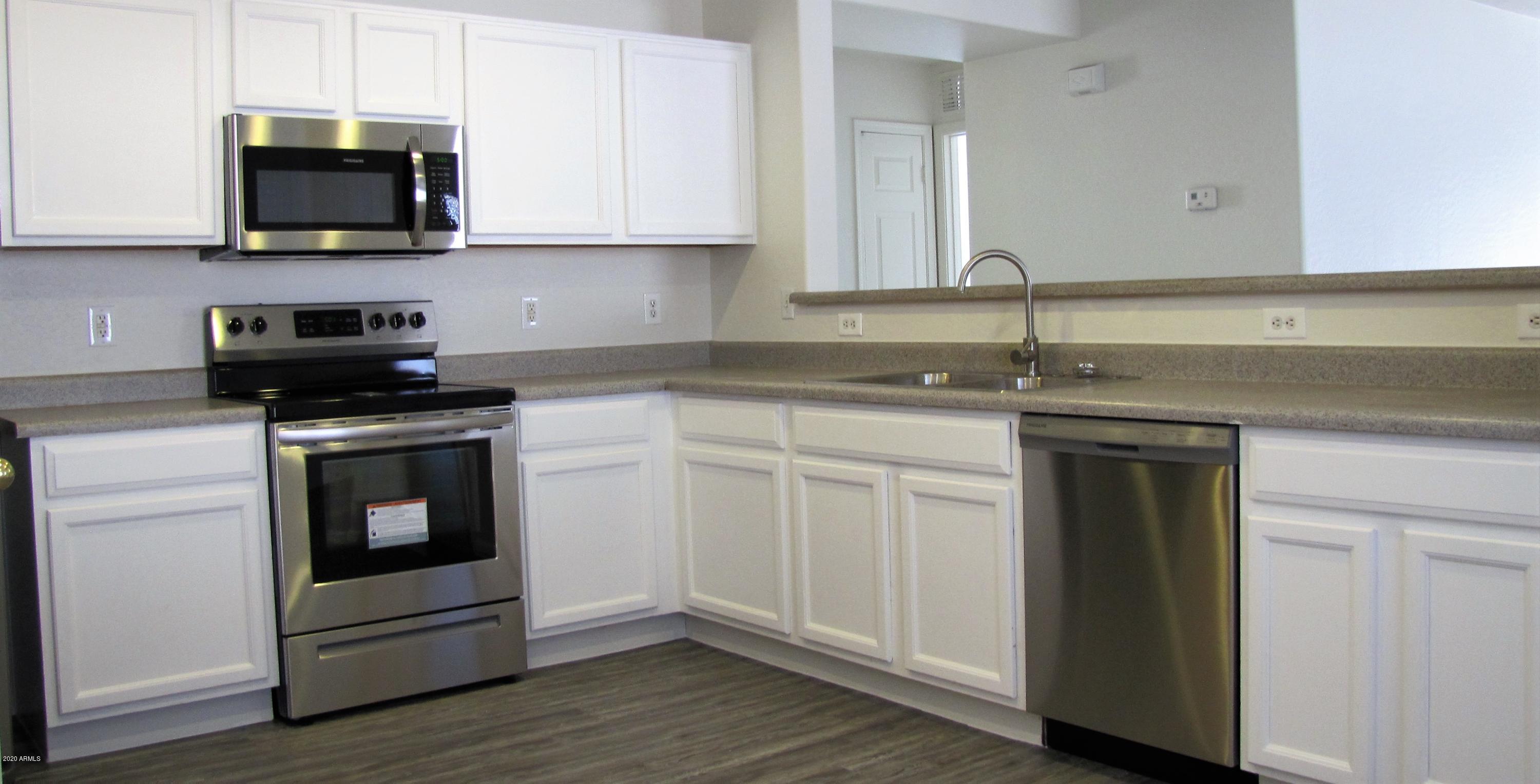 16086 West Calavar Road Surprise, AZ 85379 - Photo 7 of 28 a kitchen with white cabinets and appliances