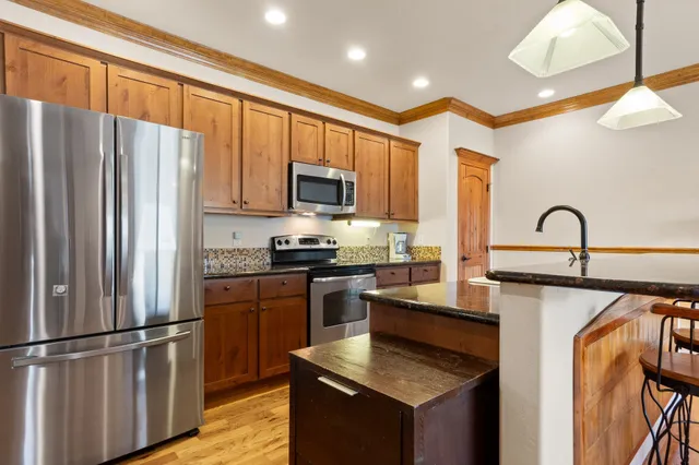 a kitchen with stainless steel appliances granite countertop a refrigerator a stove a sink and a microwave