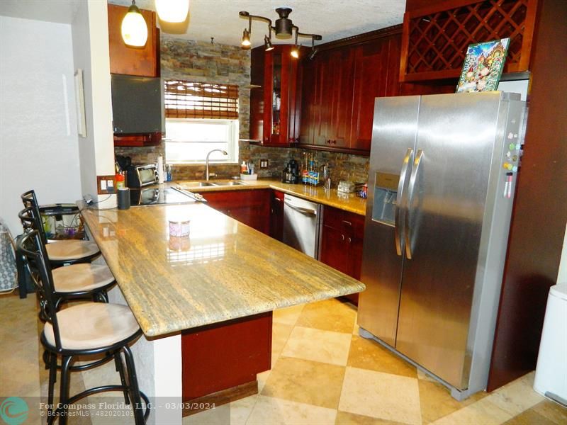 a kitchen with granite countertop a sink counter and chairs