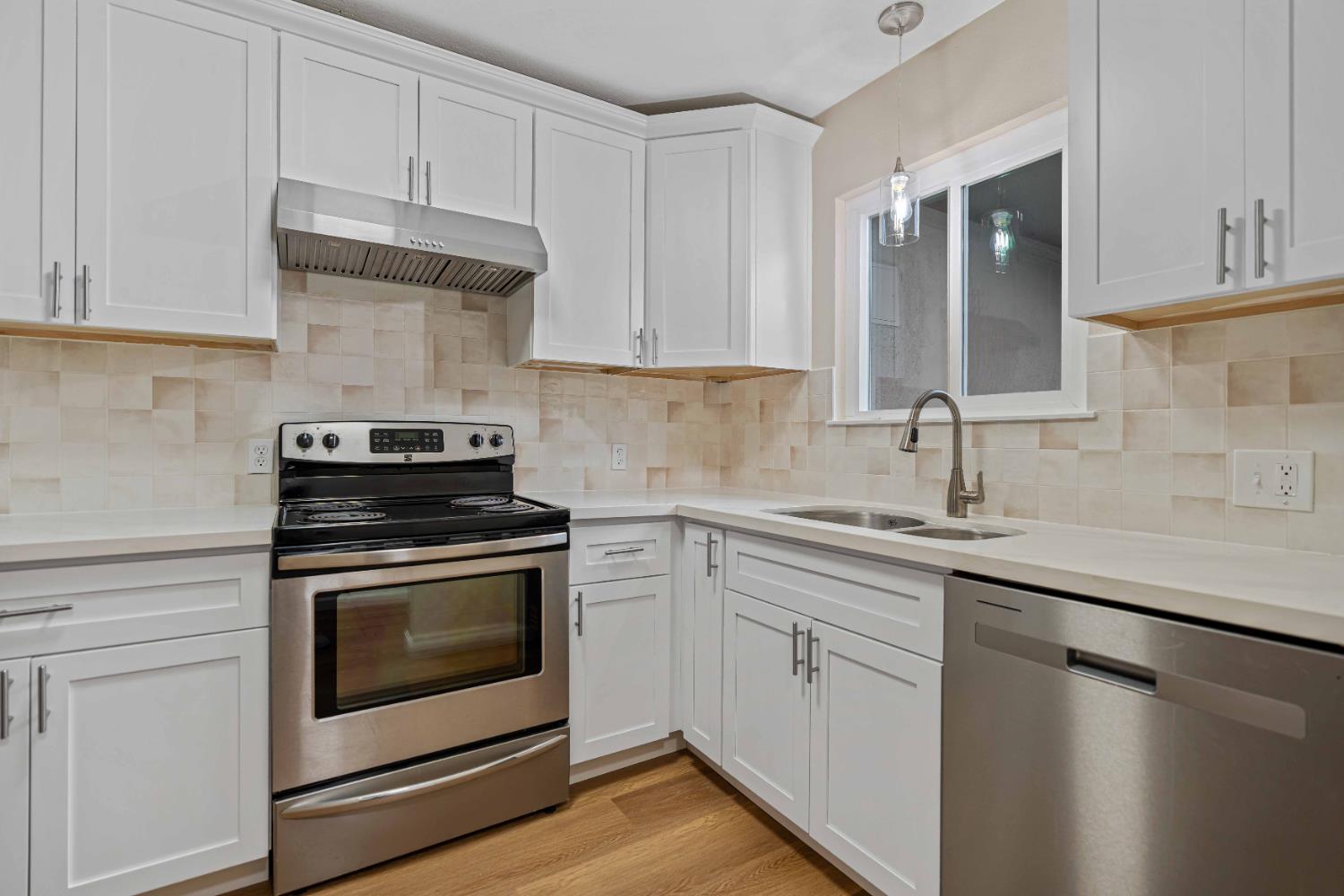 a kitchen with cabinets stainless steel appliances a sink and wooden floor