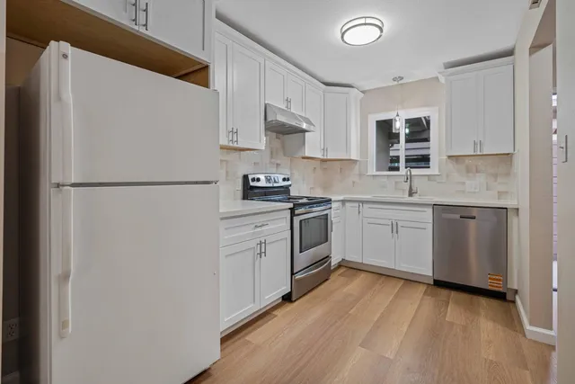 a kitchen with a sink a refrigerator and white cabinets