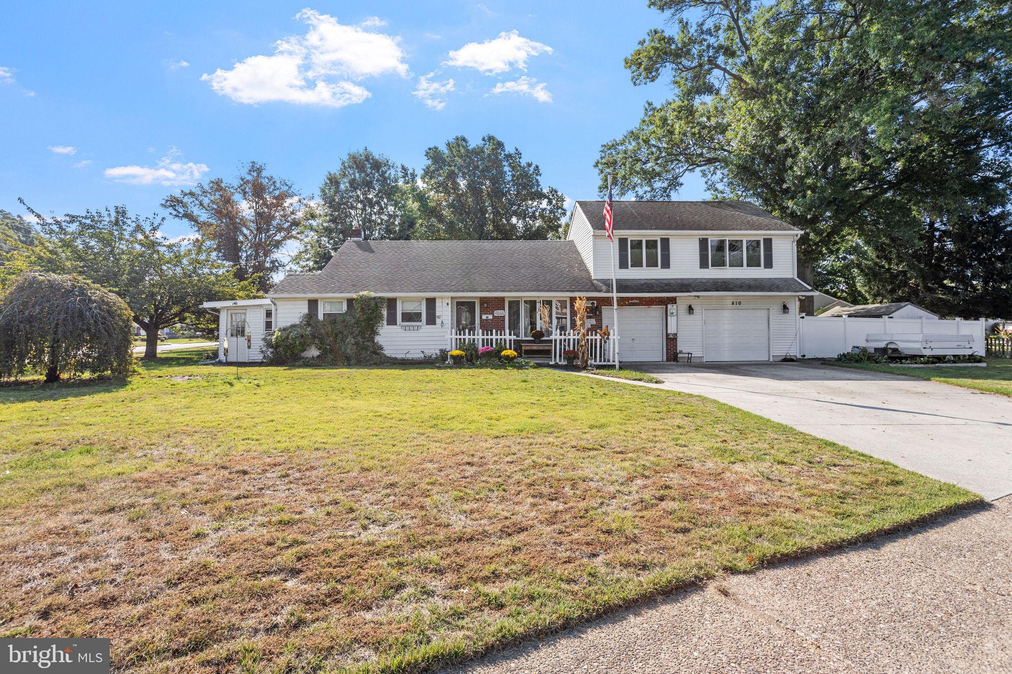 a front view of a house with swimming pool and large trees