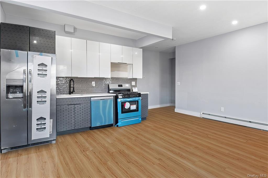 a kitchen with stainless steel appliances a sink wooden floor and a refrigerator