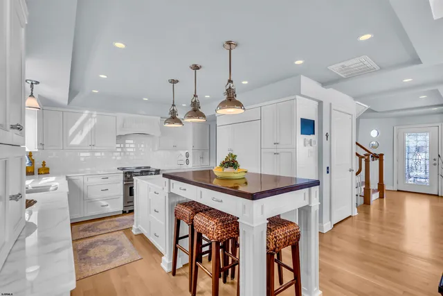 a kitchen with stainless steel appliances granite countertop a sink stove and white cabinets with wooden floor