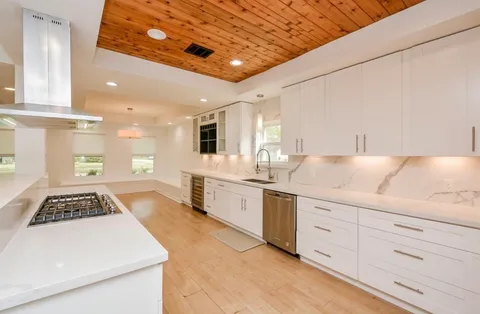a kitchen with granite countertop a stove and white cabinets
