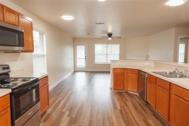 a kitchen with stainless steel appliances a stove top oven and wooden floors