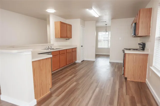 a kitchen with stainless steel appliances granite countertop a refrigerator a sink dishwasher a stove and white countertops with wooden floor