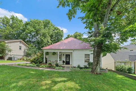 a front view of a house with a yard and trees