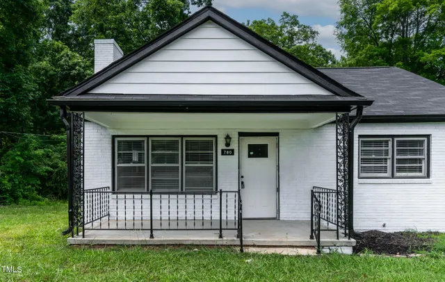 a view of a house with a small deck and a large tree