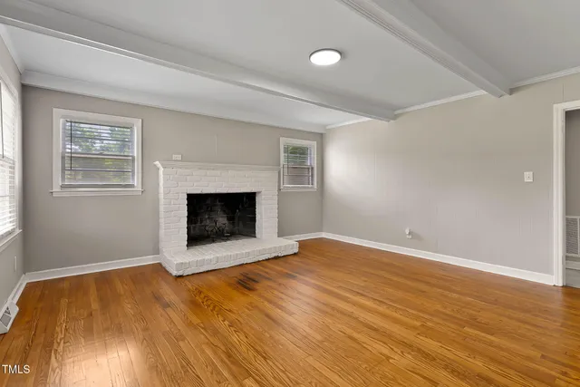 an empty room with wooden floor and fireplace