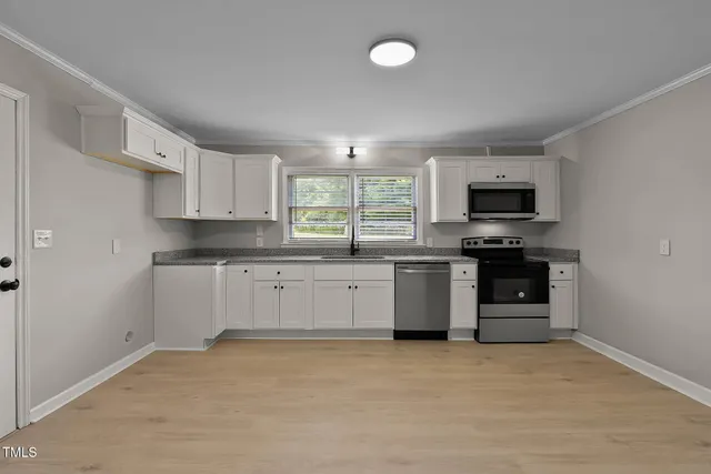 a kitchen with stainless steel appliances a stove a sink a microwave and cabinets